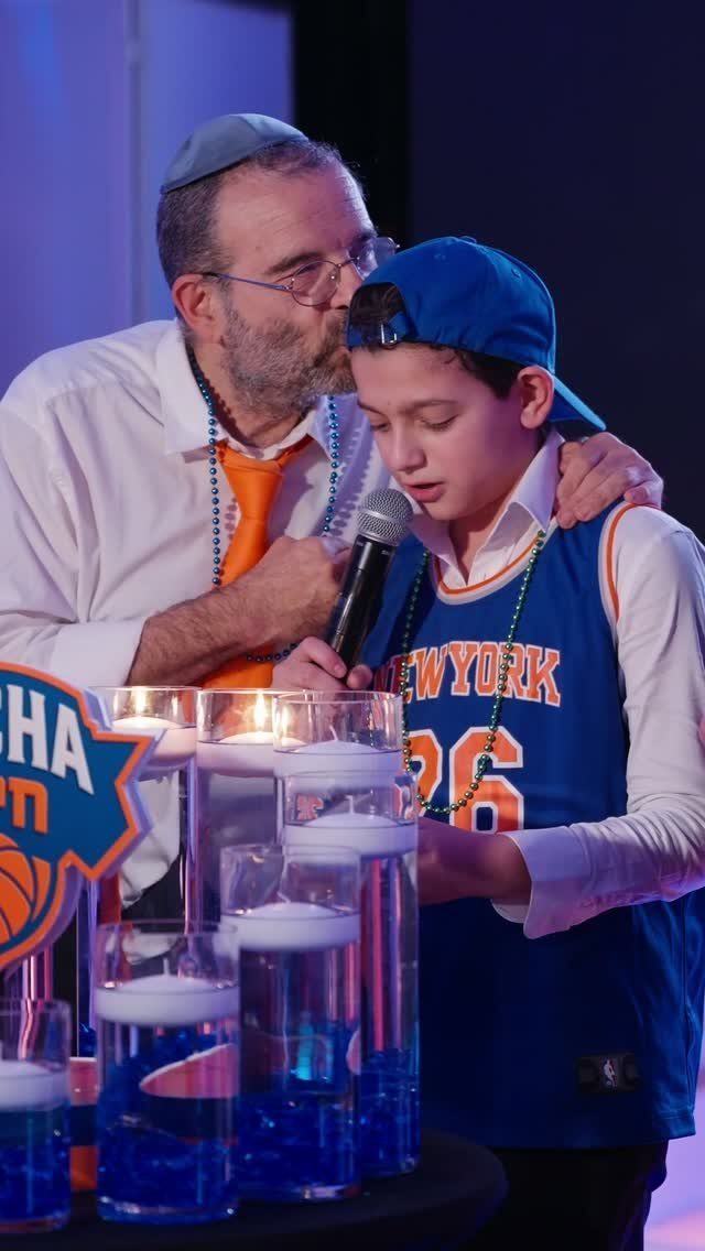 Boy in basketball jersey and man standing by blue water candle displays