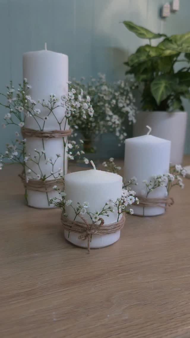 White pillar candles wrapped in twine and baby's breath flowers on wooden table