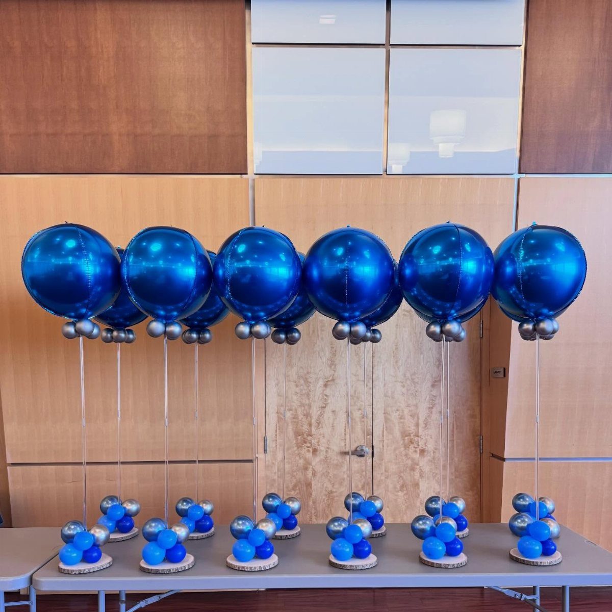 Blue metallic balloons on sticks with small balloon bases on wooden discs.