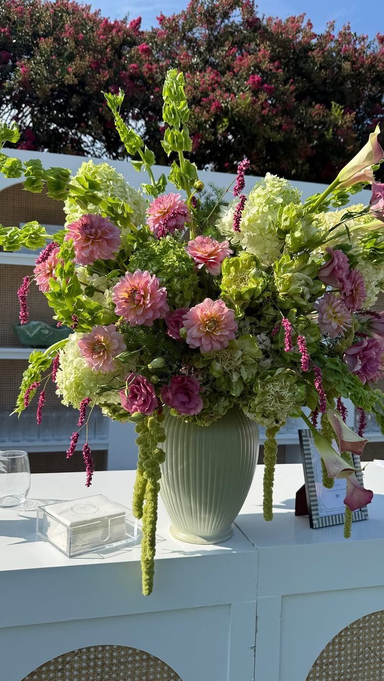 Floral centerpiece with pink and white flowers in a green vase on a table.
