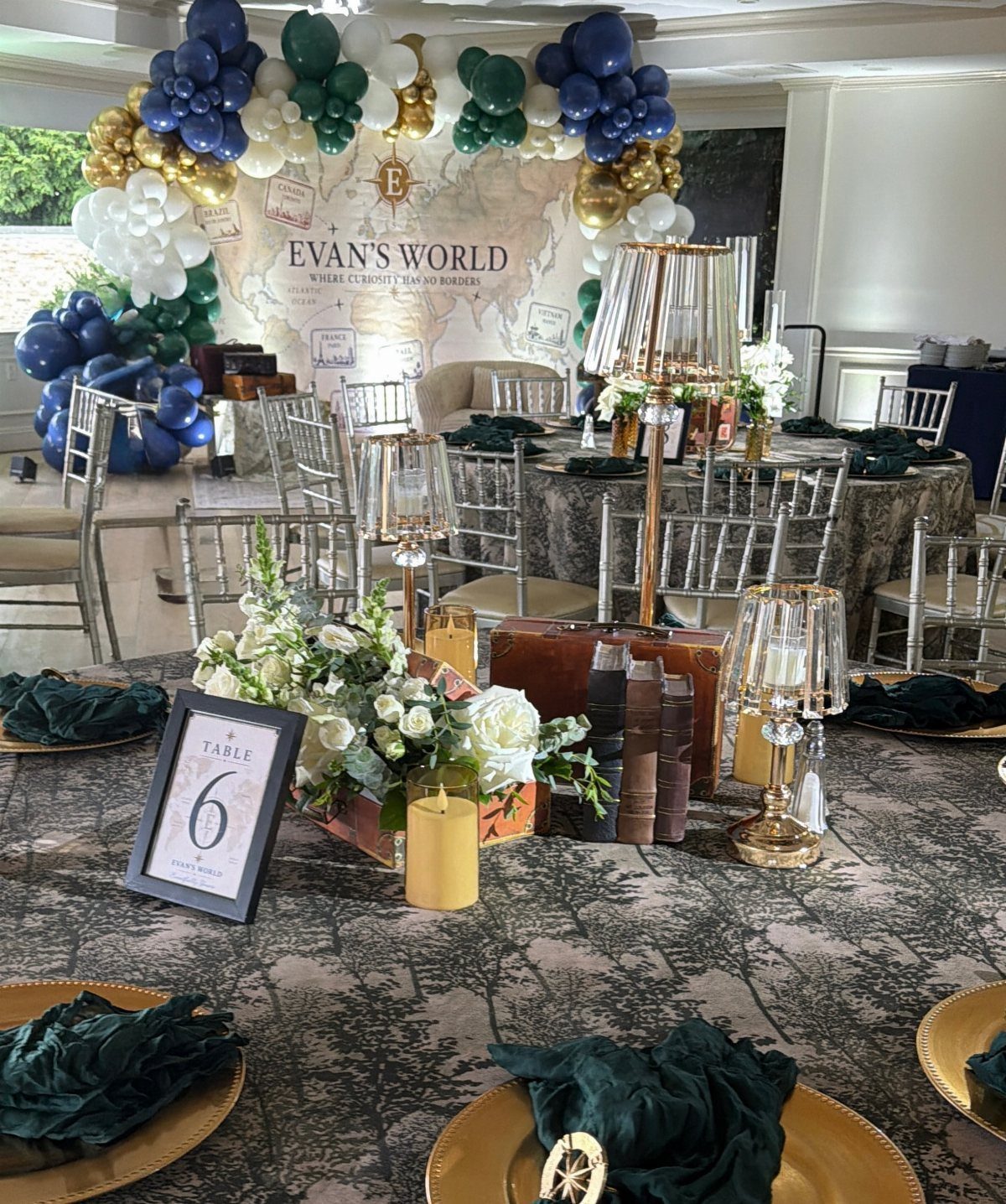 Table centerpiece with white flowers and books against a map themed backdrop