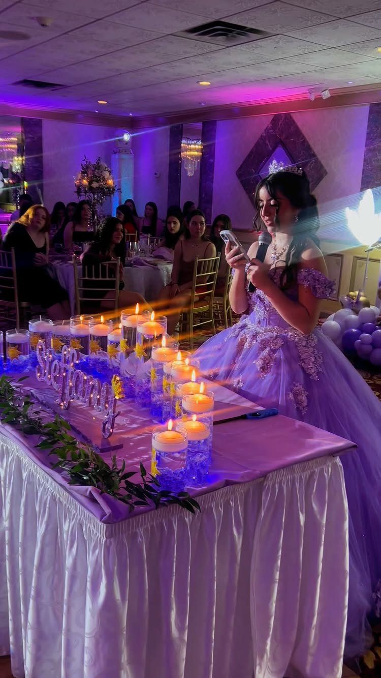 Young woman in purple gown standing by a table of lit candles