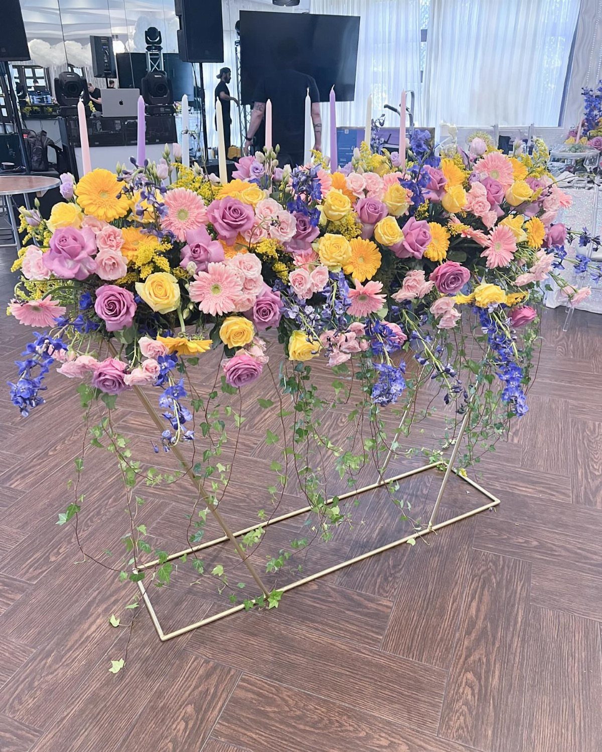 Floral arrangement with purple and white candles on a gold metal frame table.