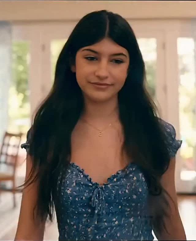 Young woman wearing a blue floral print dress with a tie-front neckline.