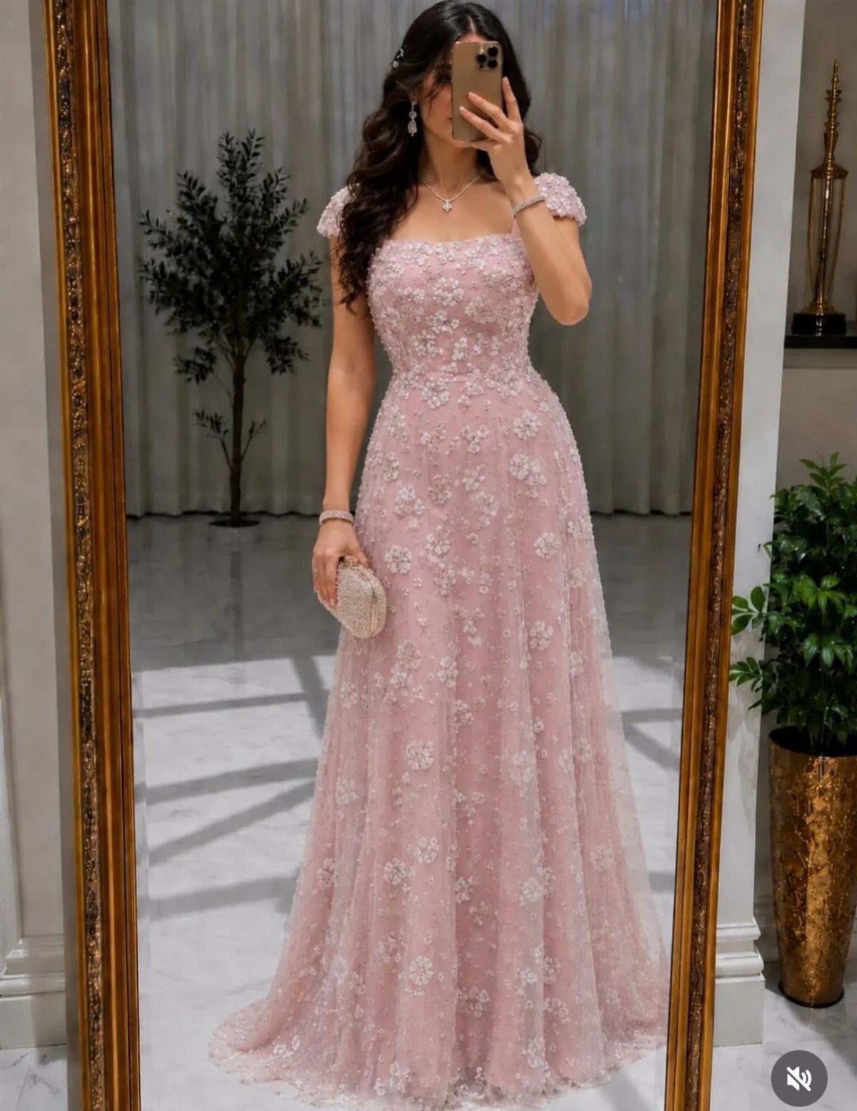 Woman in a floor-length pink floral lace gown taking a mirror selfie.