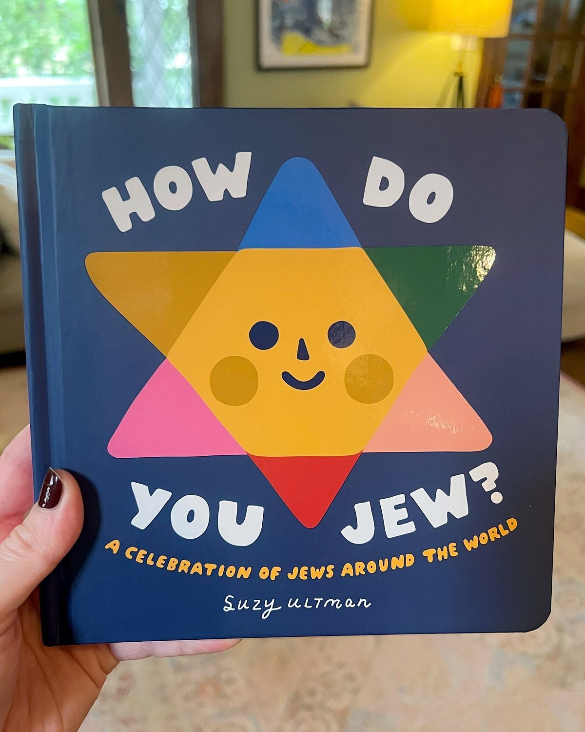 A colorful children's book about Jewish culture held by a person's hand.
