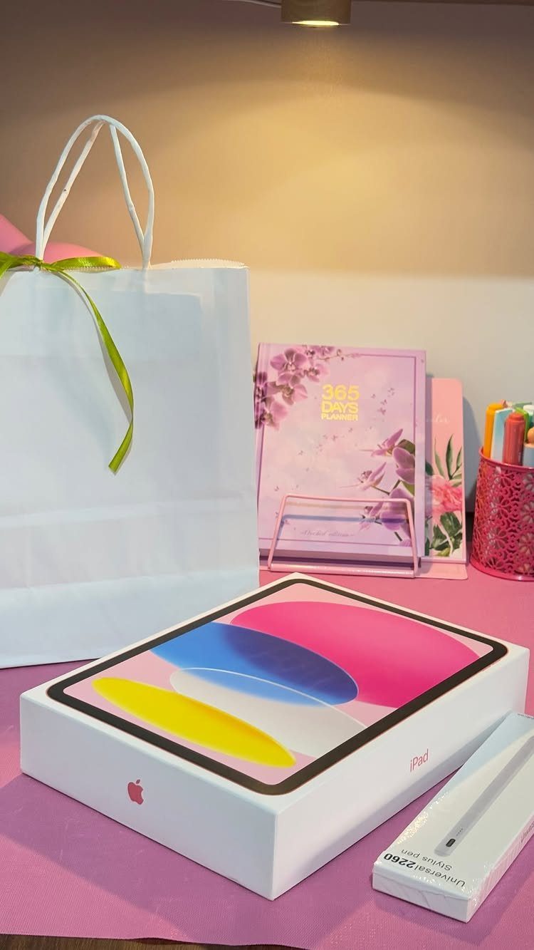 iPad and Apple Pencil gift boxes with a white gift bag and stationery.