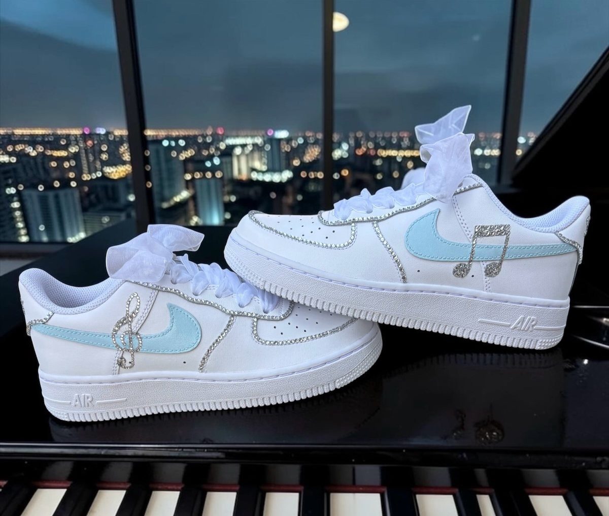 White Nike sneakers with blue swooshes and glitter musical notes on a piano
