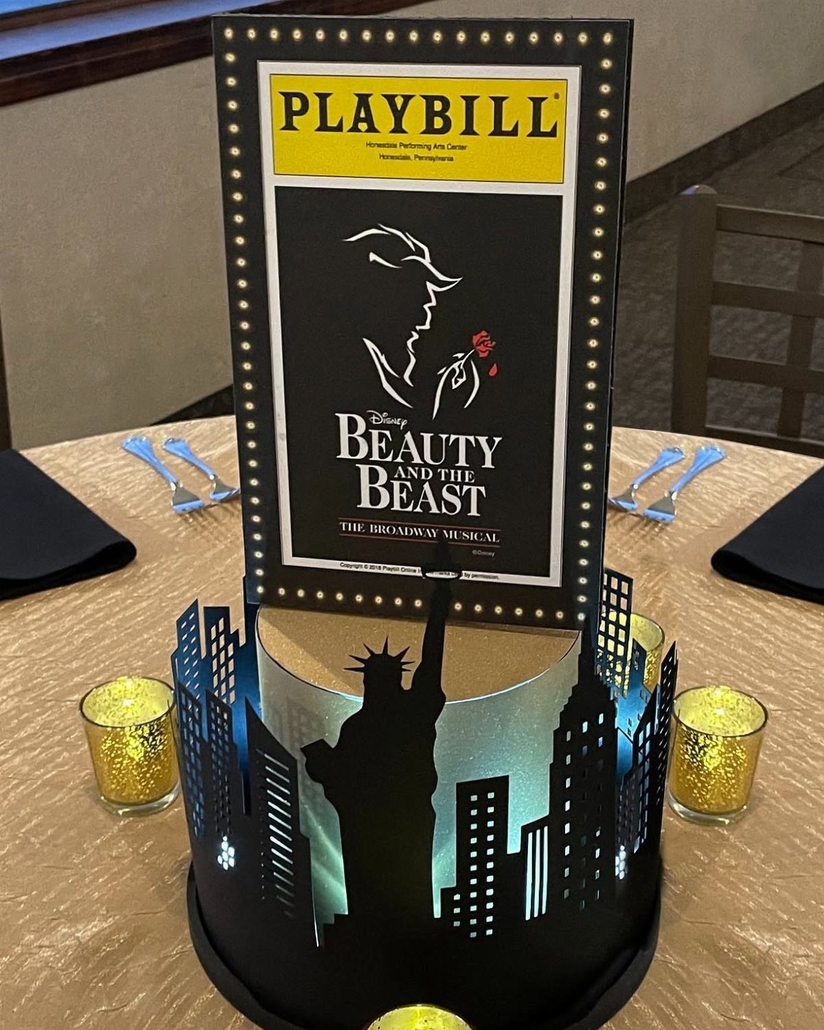 Broadway themed centerpiece with a Beauty and the Beast Playbill and NYC skyline silhouette