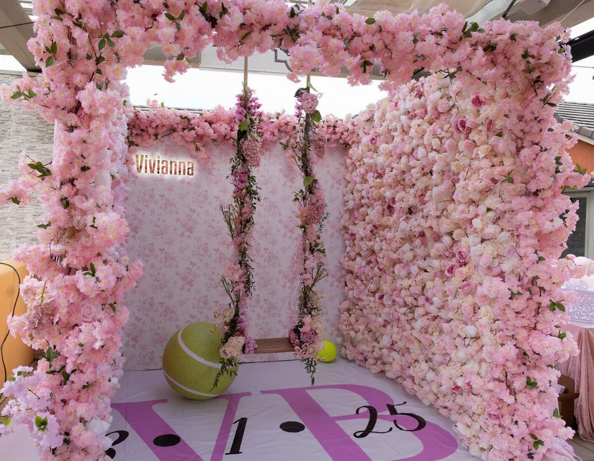 Pink flower wall and archway with a swing for a party backdrop