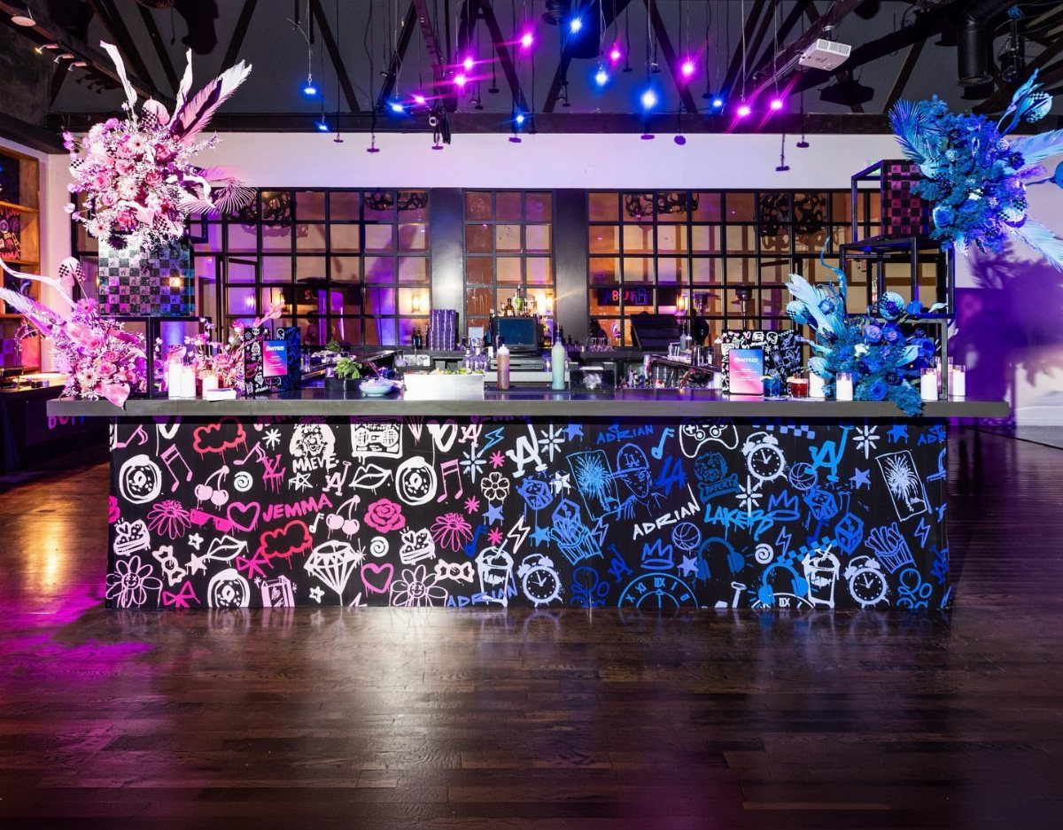 Graffiti-style bar counter with pink and blue doodles in a dimly lit venue.
