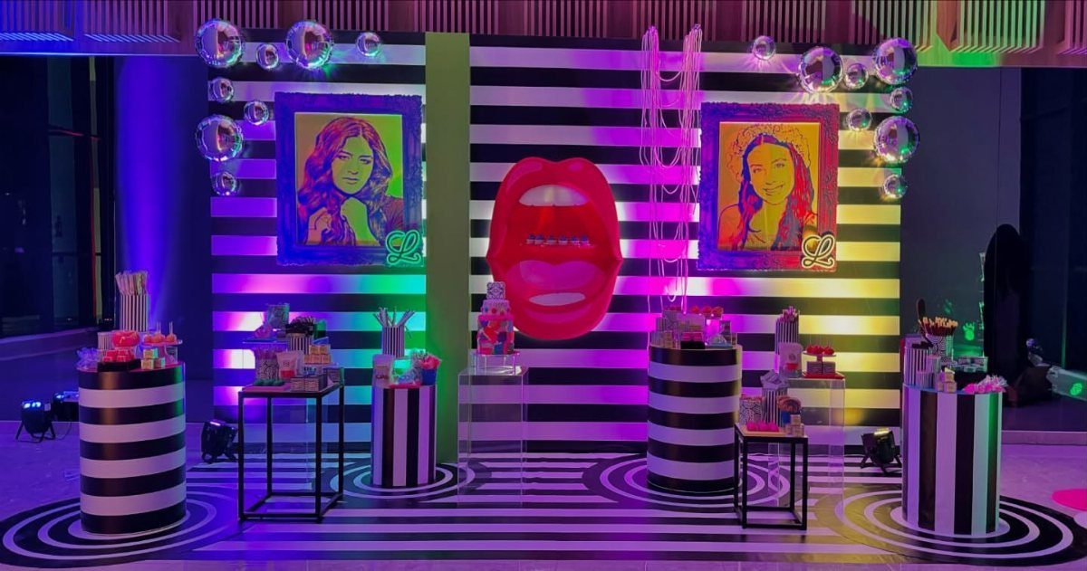 Pop art party decor with striped patterns, colorful portraits, and a large red lip.