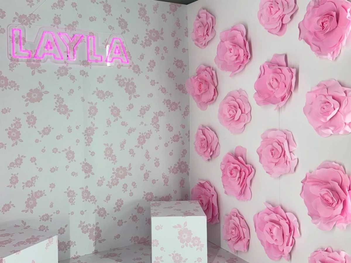 Photo booth backdrop with pink paper roses and a neon sign reading LAYLA