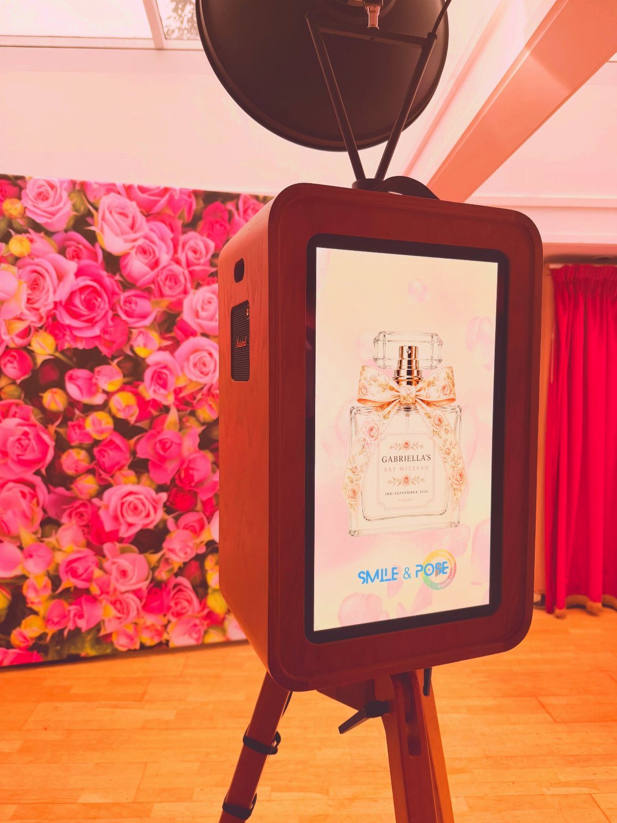 Wooden photo booth kiosk with a pink rose flower wall backdrop