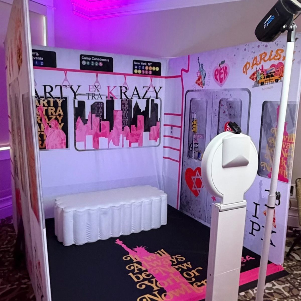 New York City themed photo booth with pink skyline backdrop and digital kiosk.