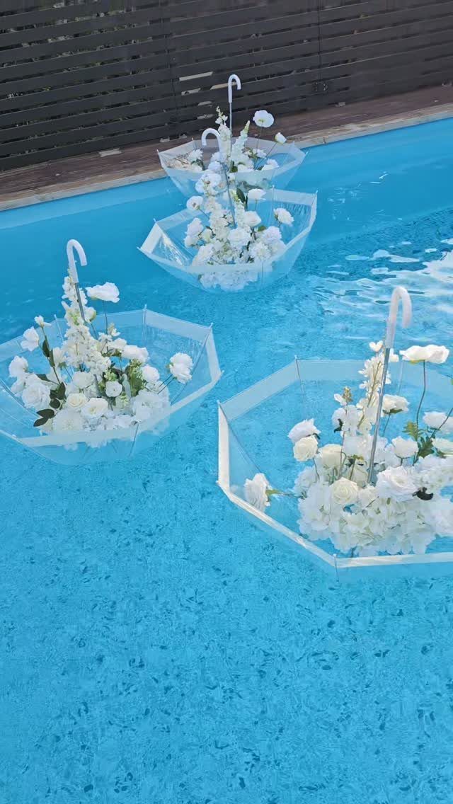 Hexagonal clear trays with white roses floating in a bright blue swimming pool