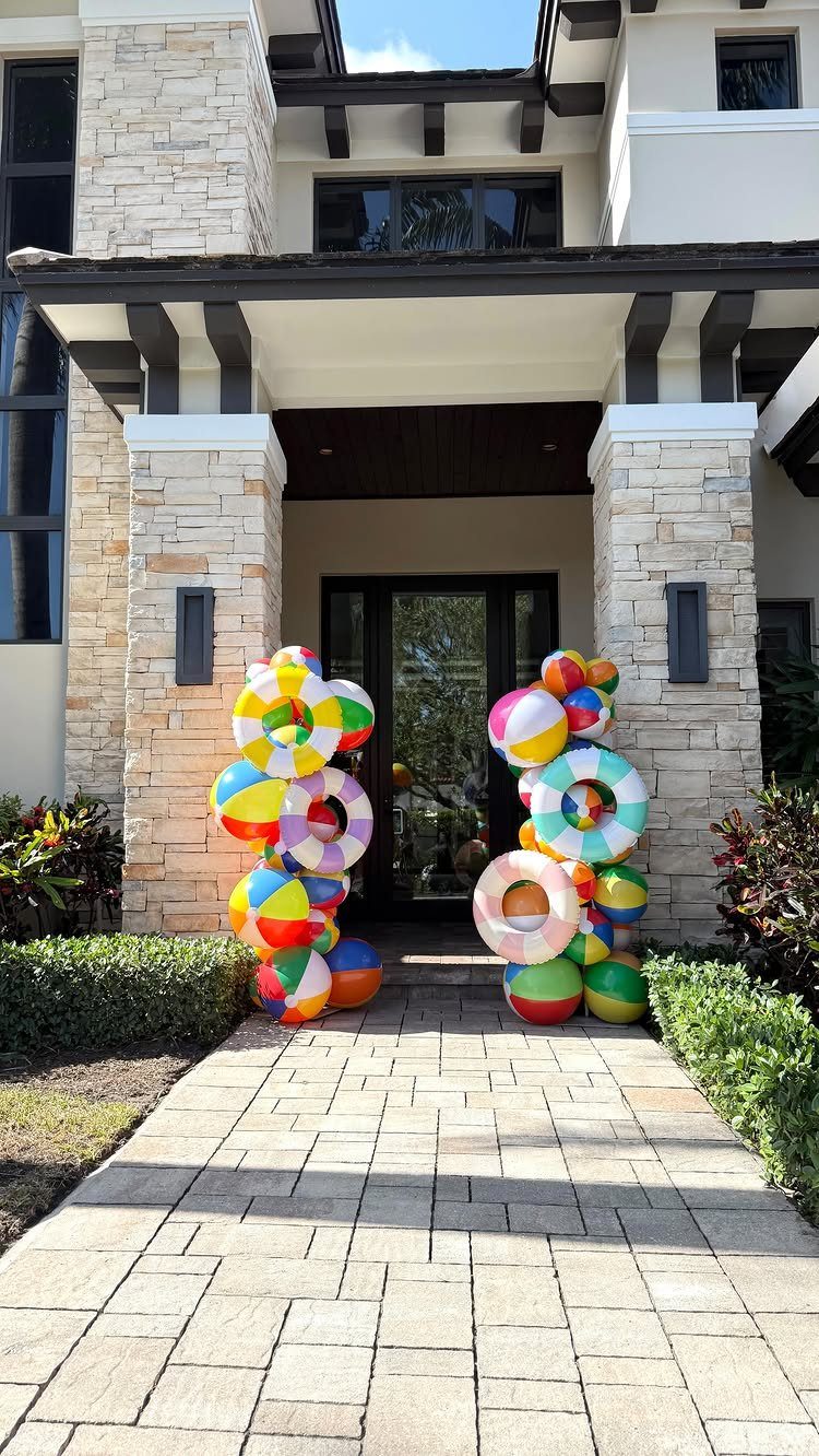 Colorful beach balls and inflatable rings decorating the entrance of a stone house.