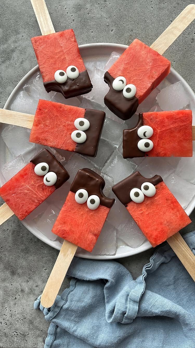 Watermelon popsicles dipped in chocolate to look like sharks on a plate of ice.
