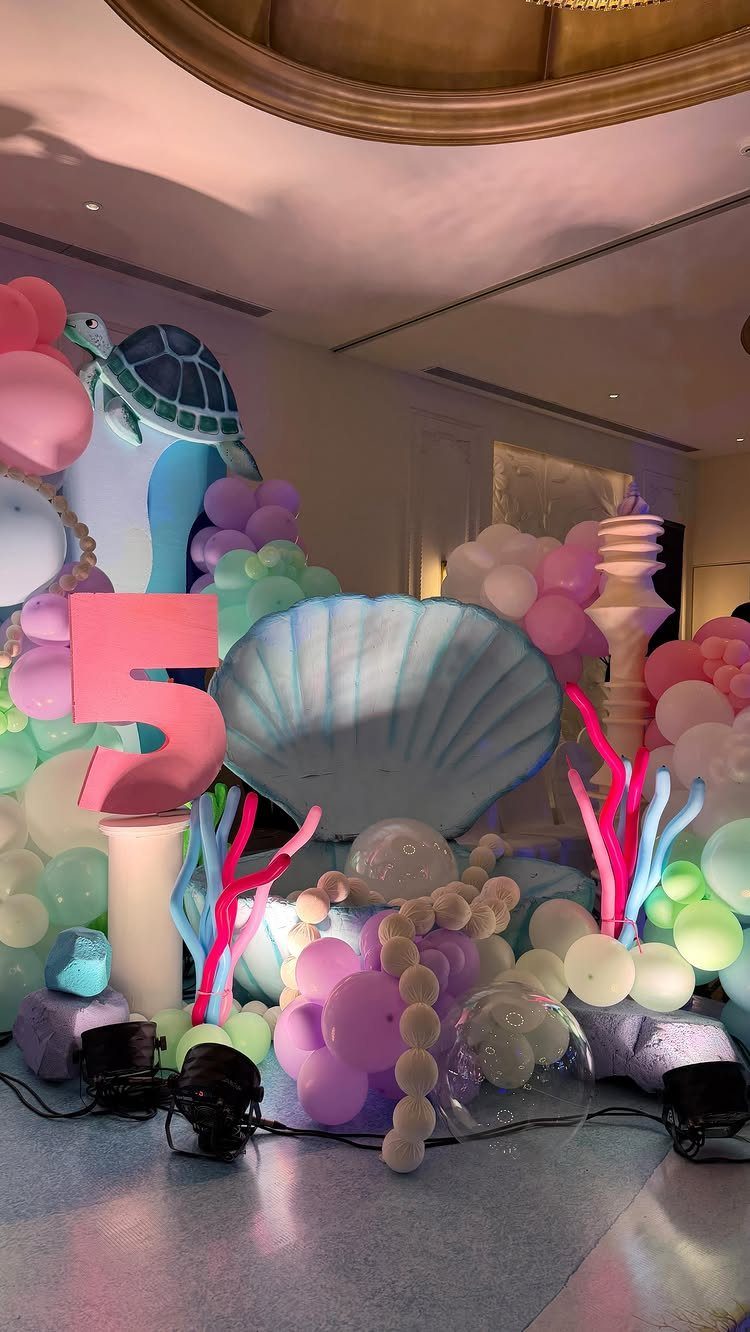 Undersea party decorations with a large seashell, pastel balloons, and a sea turtle.