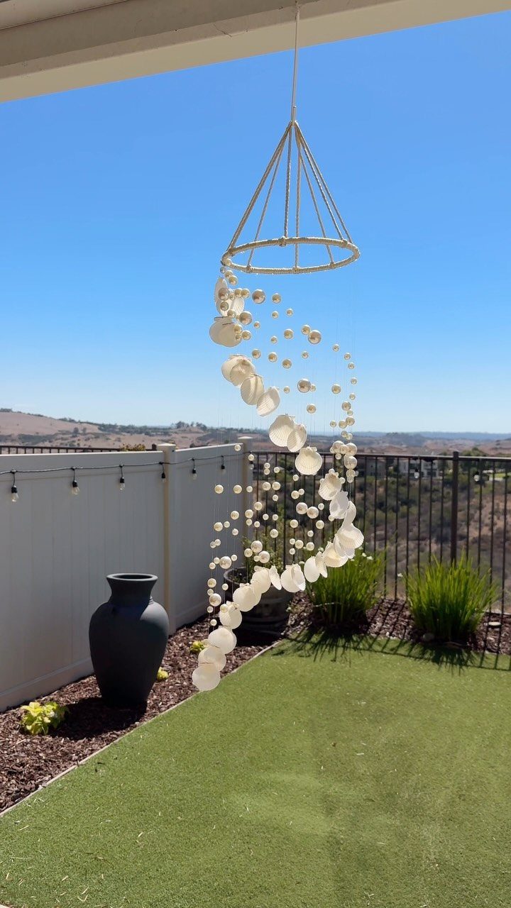 Handmade hanging decoration with white shells and beads cascading from a conical frame.