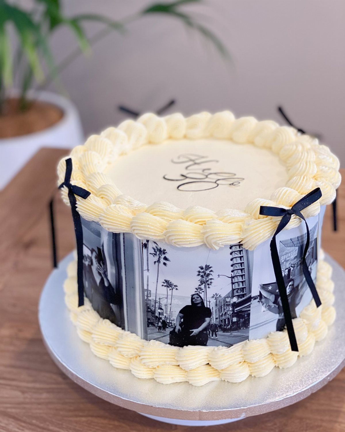 Round cake with edible black and white photos on the sides and yellow frosting.