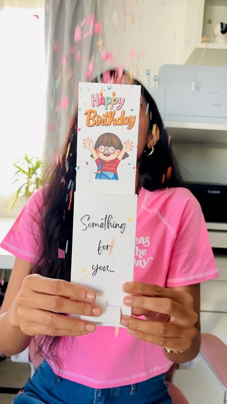 Handmade birthday card held by a person with colorful confetti falling around it