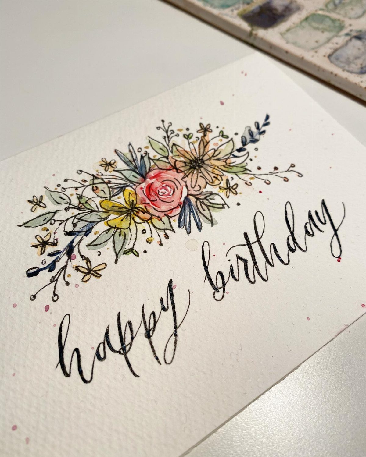 Handmade birthday card with watercolor floral doodles and black modern calligraphy text.
