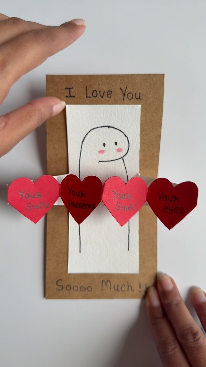 Handmade card with a simple character drawing and four red paper hearts.