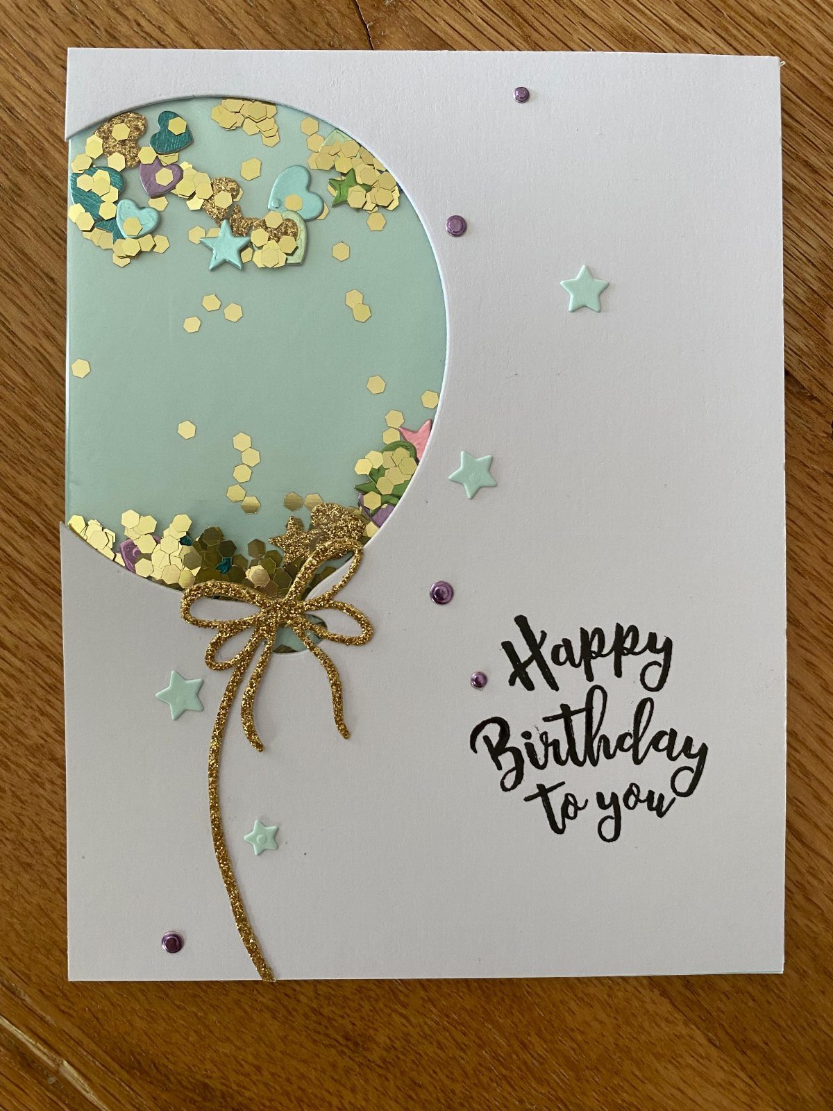 Handmade birthday card with a sequin-filled balloon and gold glitter bow.