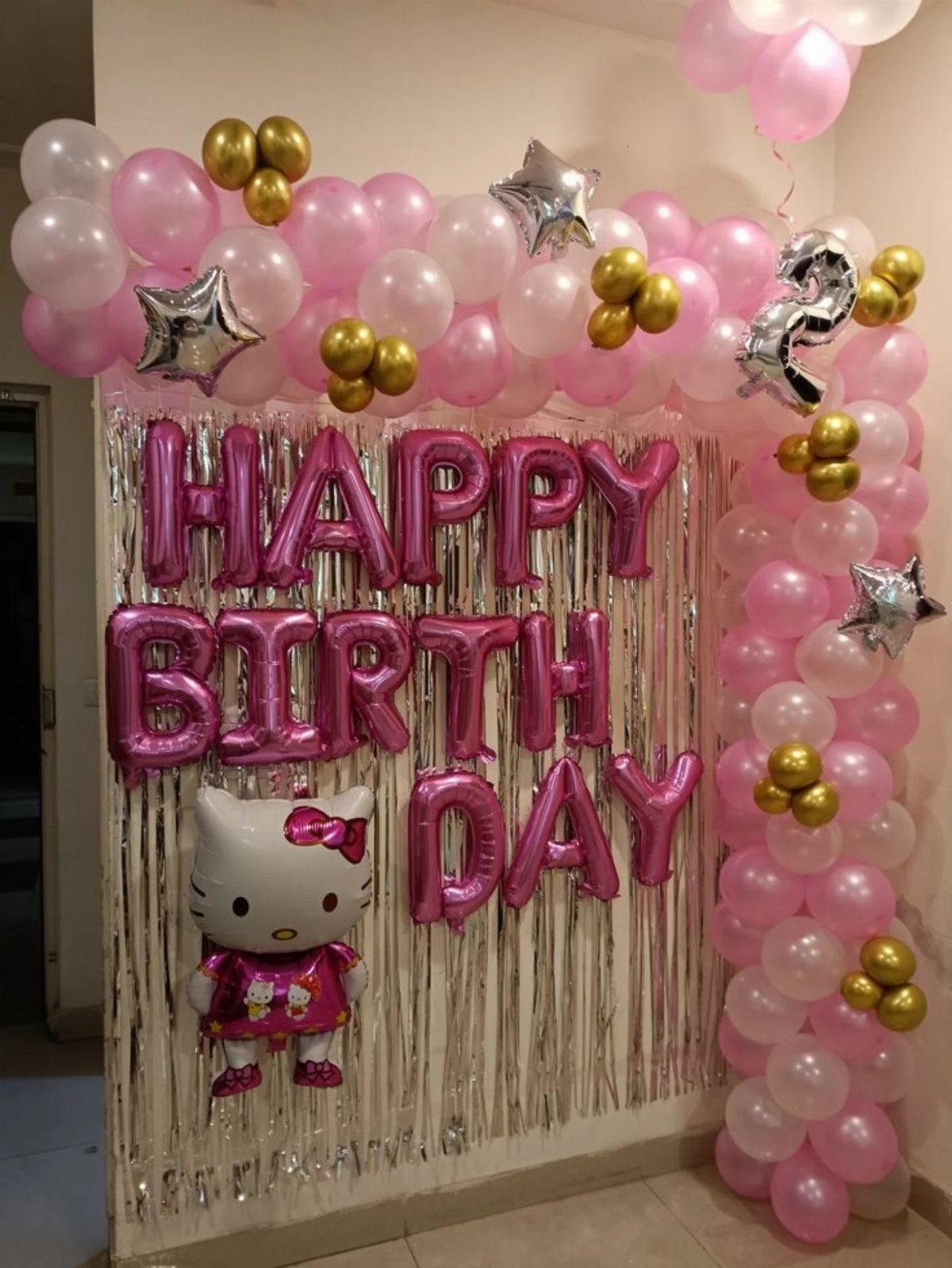 Pink and white balloon garland framing a silver fringe curtain with birthday balloons.