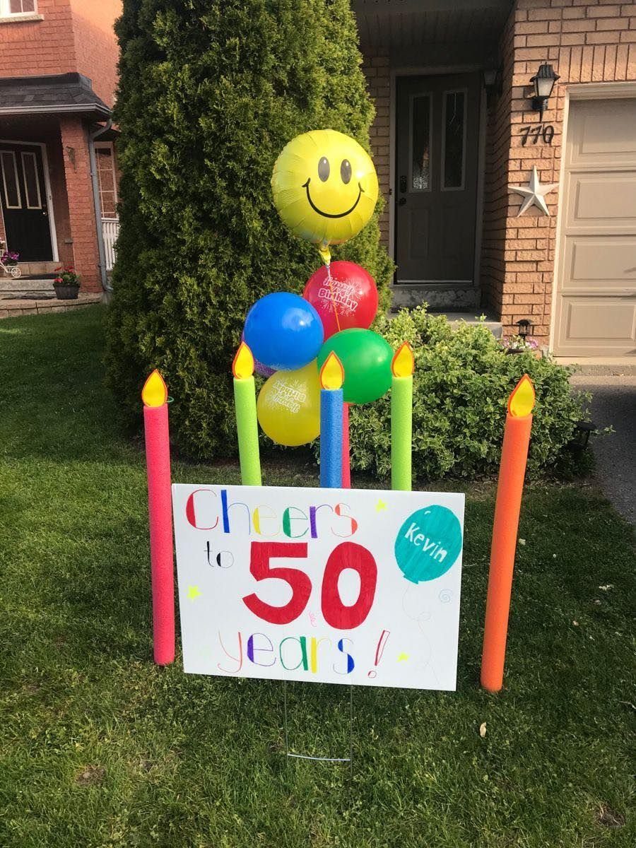 Large colorful candle stakes and balloons next to a 50th birthday sign outdoors.