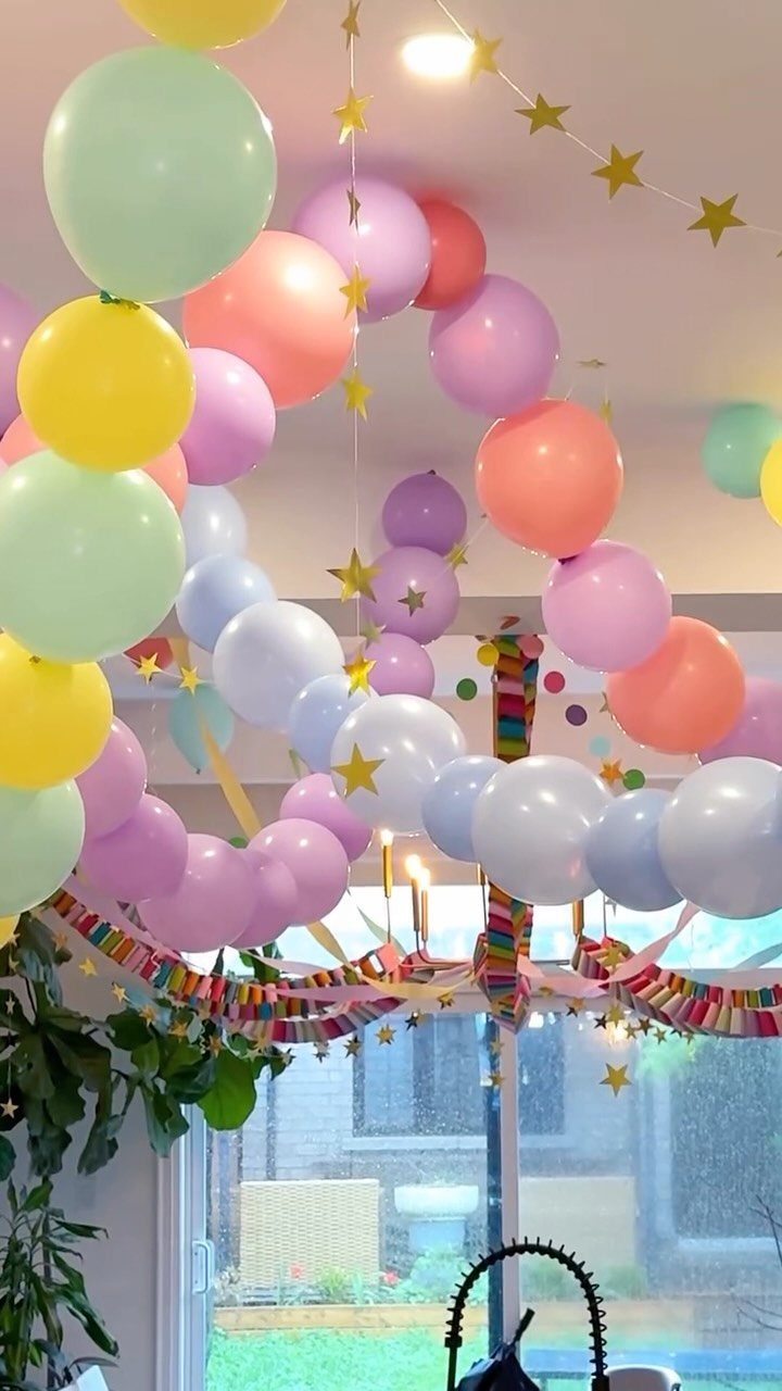 Pastel balloon garland with gold stars hanging from a ceiling indoors.