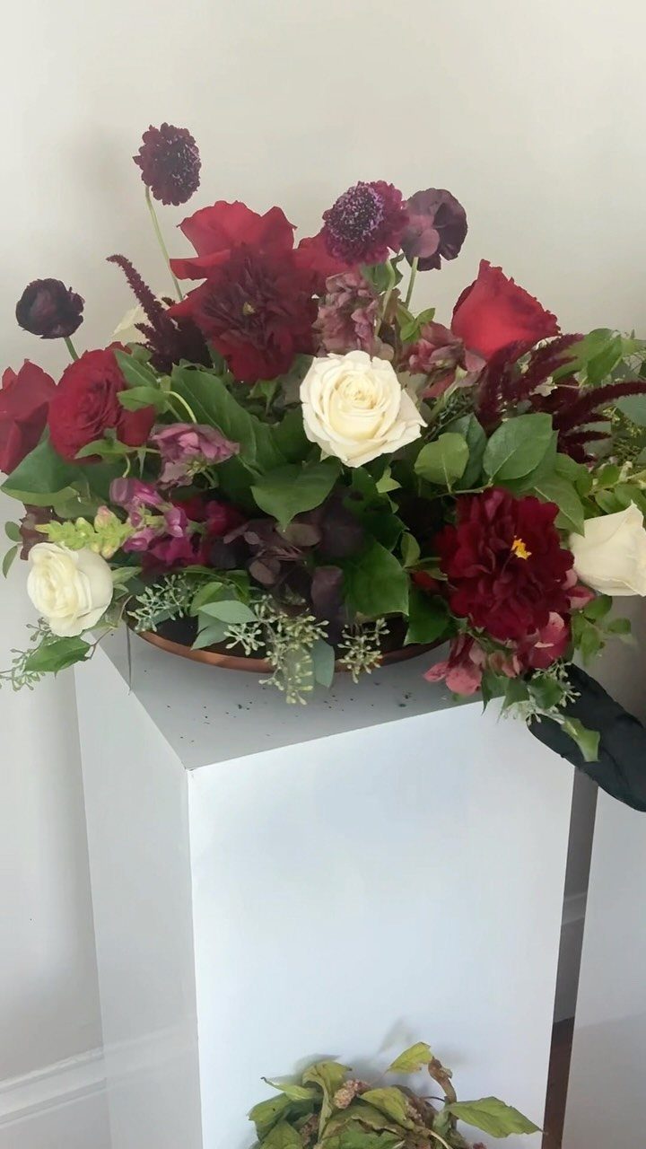 Floral arrangement with red and white roses on a white pedestal