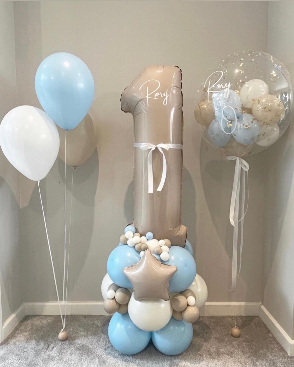 Blue, white, and gold balloons including a large number one for a birthday.