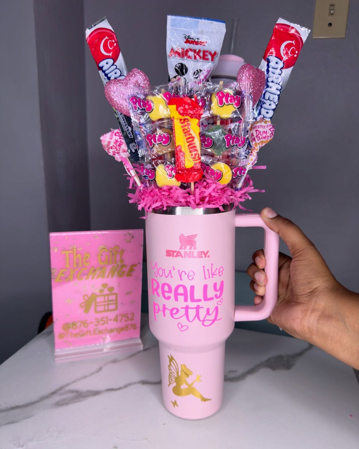 Pink Stanley tumbler filled with colorful candies and lollipops as a gift set.