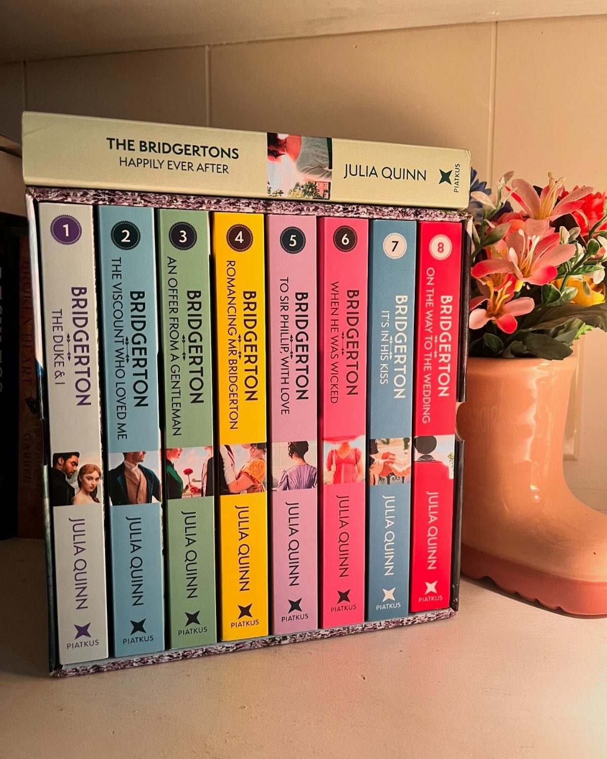 The Bridgertons boxed book set with colorful spines next to orange flowers