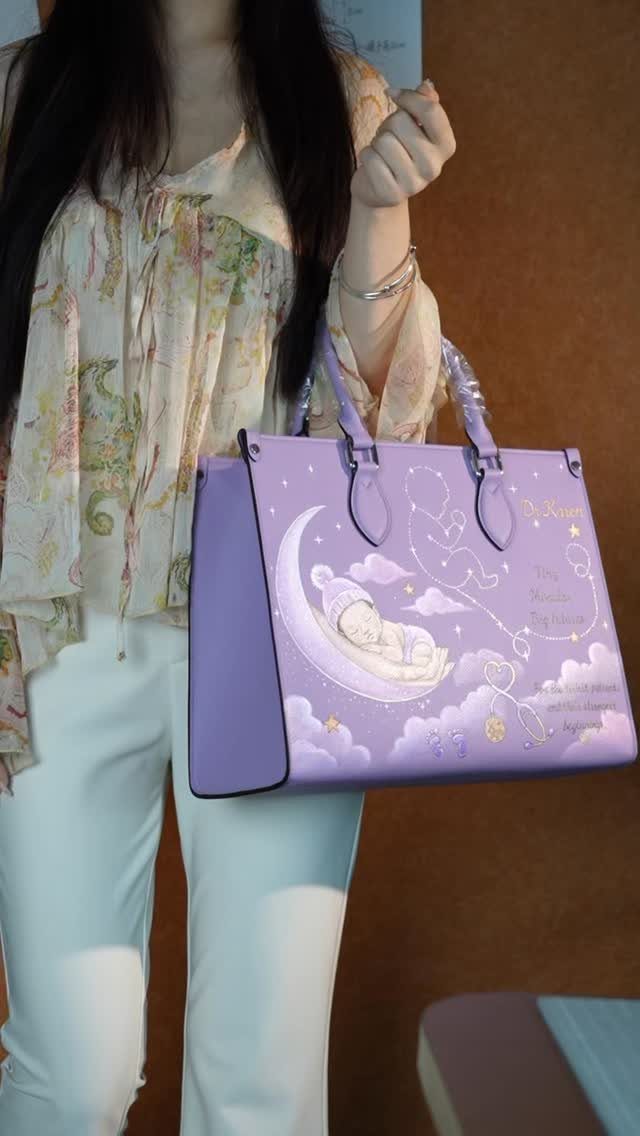 Purple leather tote bag with a sleeping baby on a moon illustration.