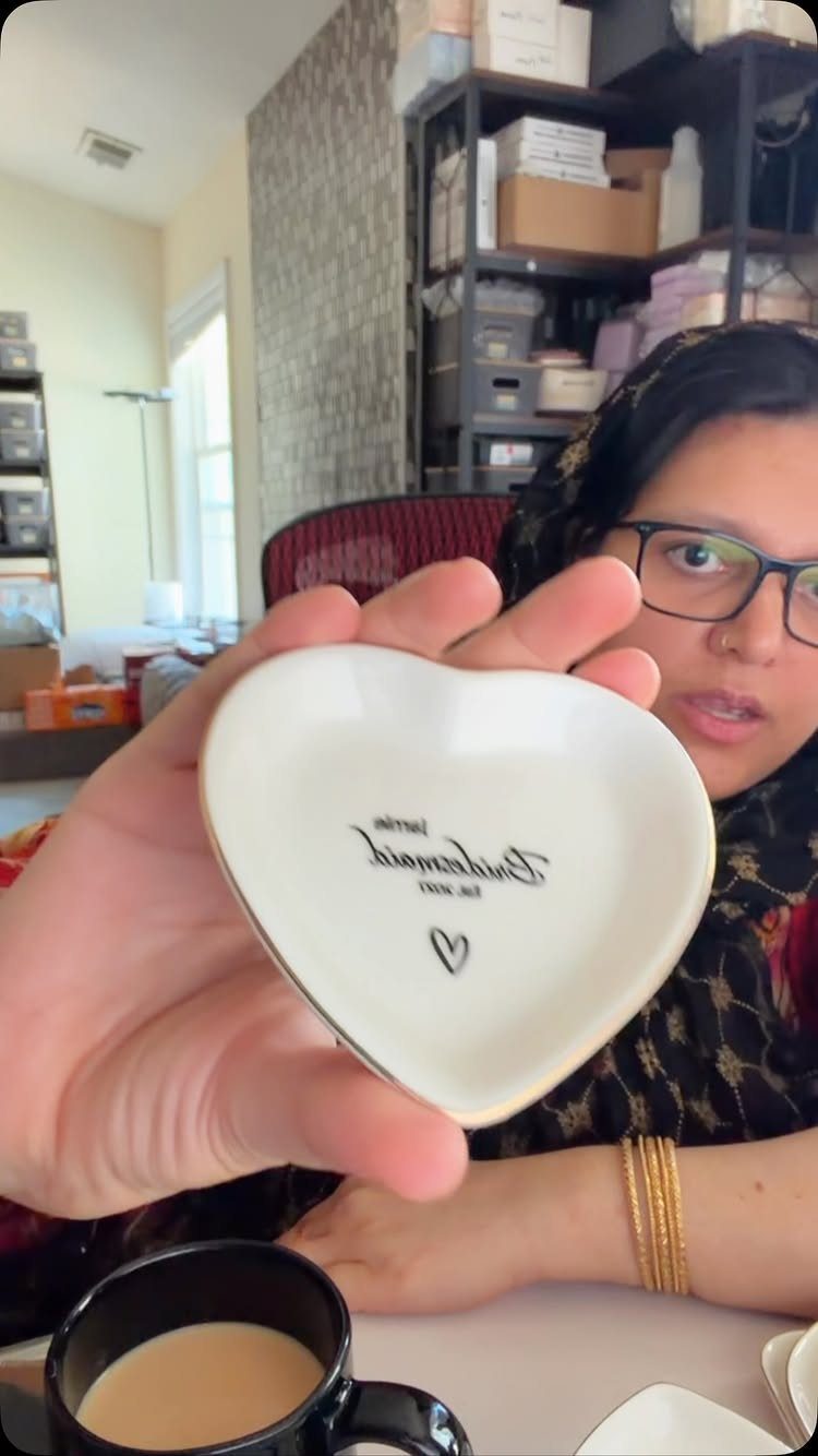 Heart-shaped white ceramic trinket dish with gold rim held by a person.