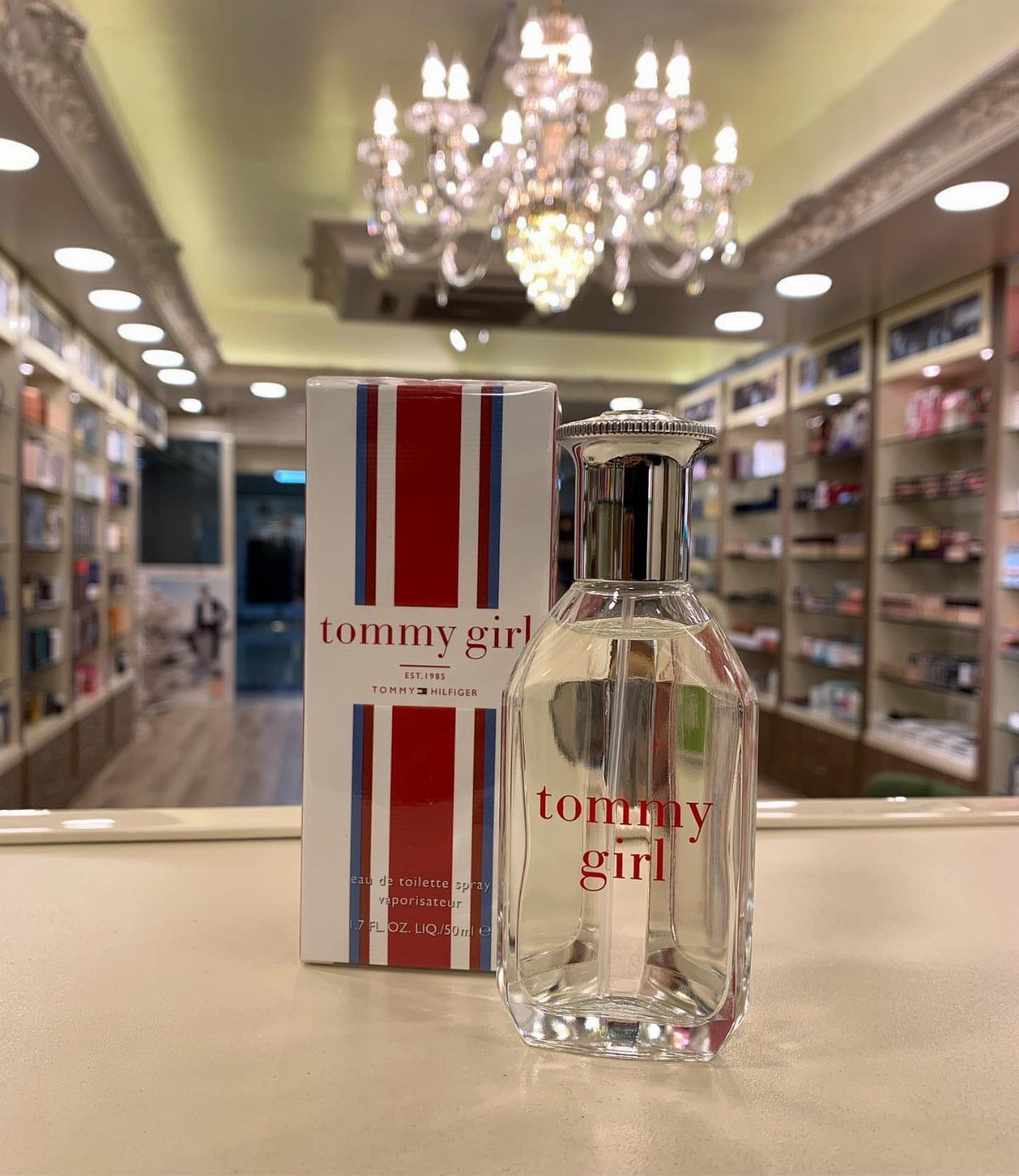 Tommy Girl perfume bottle and striped box on a counter in a store