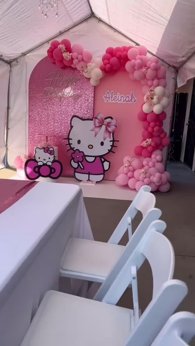 Pink heart-shaped balloon arch and Hello Kitty backdrop for a birthday party setup.