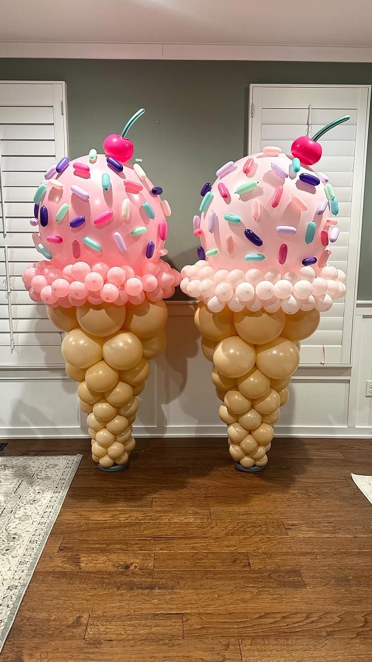 Two ice cream cone balloon columns with pink scoops and colorful sprinkles.