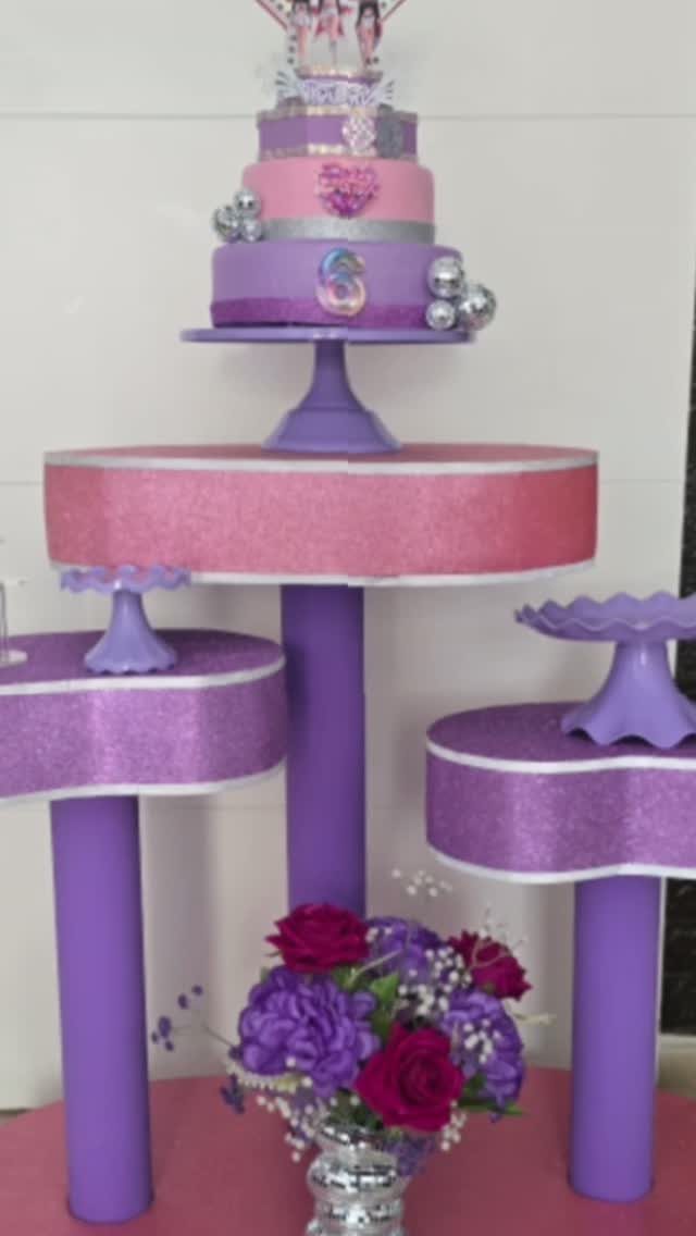 Tiered purple and pink glittery cake stands holding a decorated birthday cake.