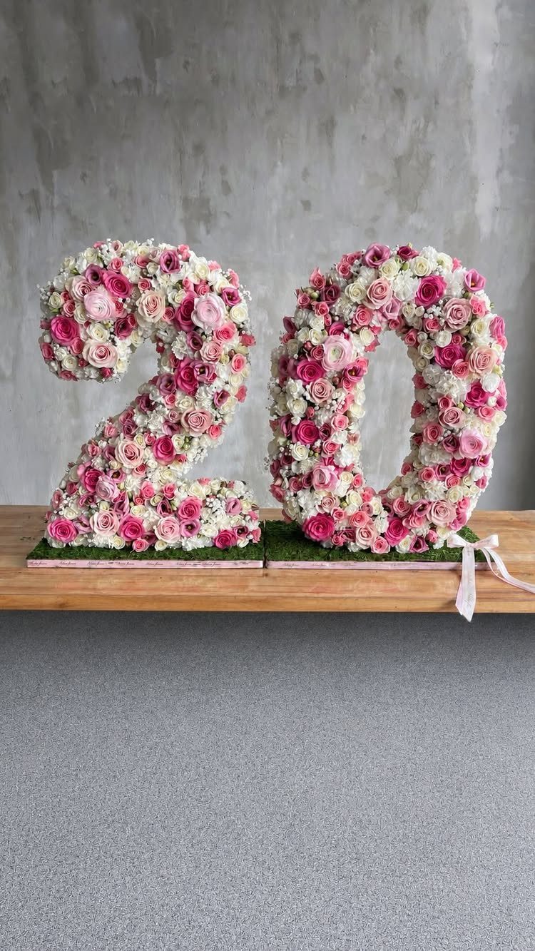 Large numbers 20 crafted from pink and white roses on a wooden table.