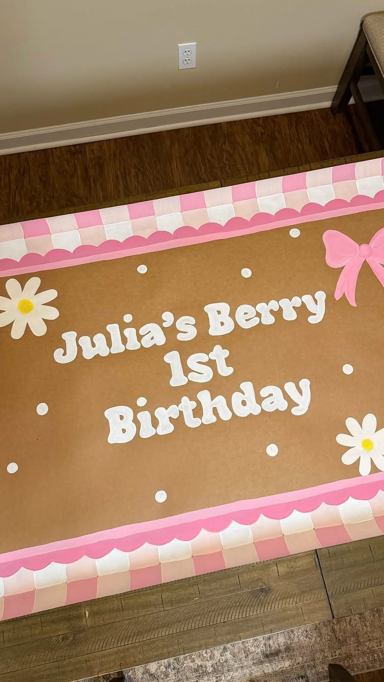 Personalized birthday banner for Julia's 1st birthday with pink checkered borders and daisies.