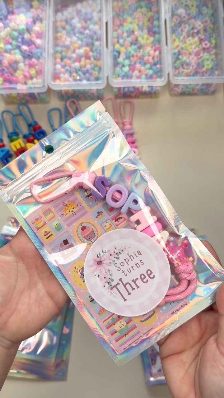 Personalized beaded bracelet in a holographic bag for a third birthday party favor.