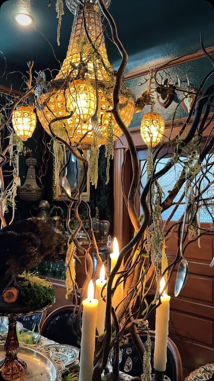 Ornate golden chandelier and glowing lanterns amidst twisted branches and lit white candles.