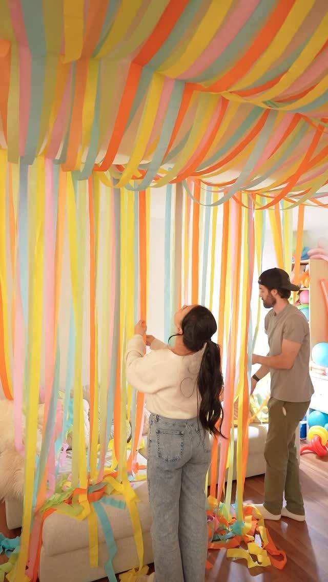 Colorful streamers hanging from the ceiling and walls in a festive home setting.