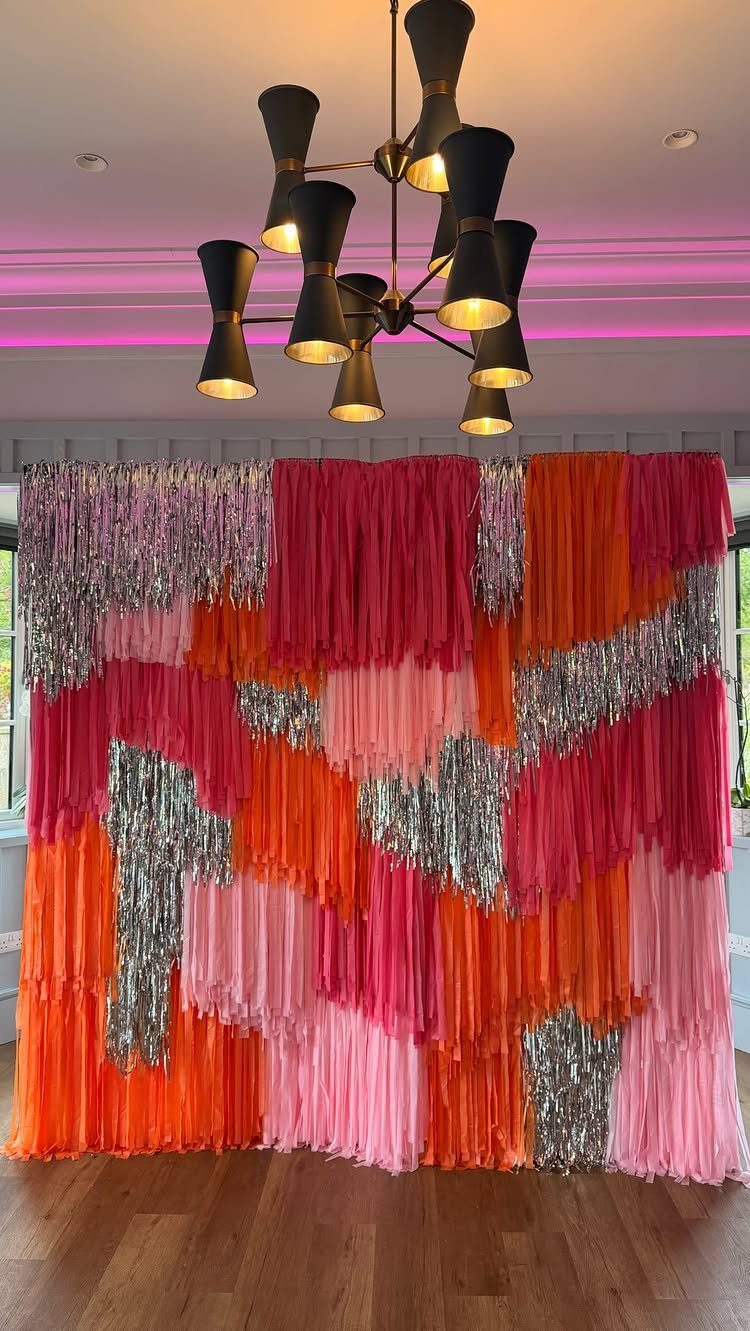 Colorful pink, orange, and silver tinsel fringe backdrop in a modern room.