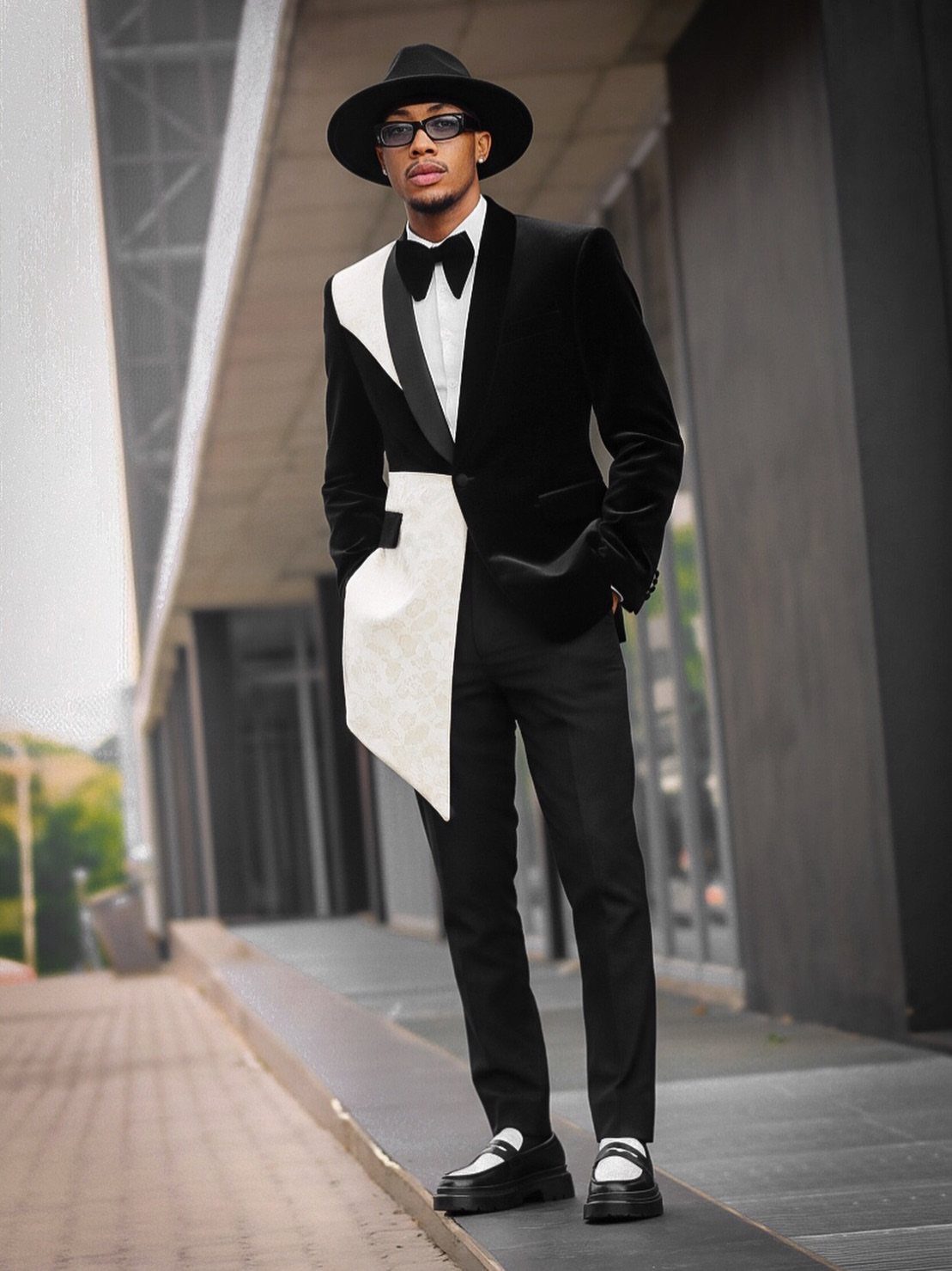 Man in a stylized black and white tuxedo with a black hat and sunglasses.