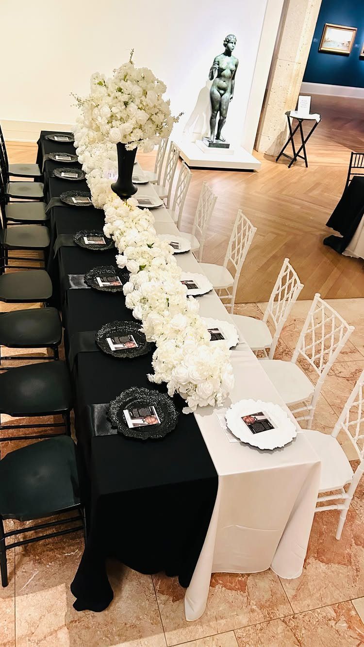 Long dining table with split black and white linens and white floral runner.
